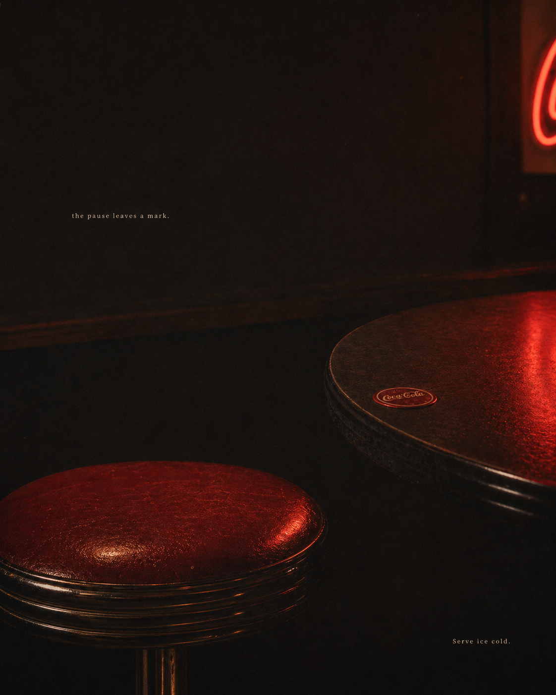 A single red bar stool beside a marble table edge, neon Coca-Cola reflecting on the surface